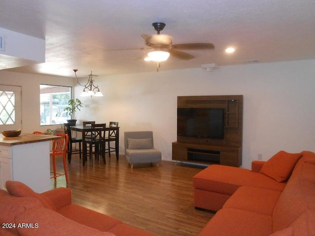 living room with hardwood / wood-style floors and ceiling fan with notable chandelier