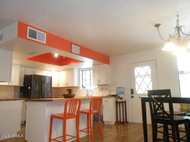 kitchen with dark wood-type flooring, fridge, a breakfast bar, and white cabinets