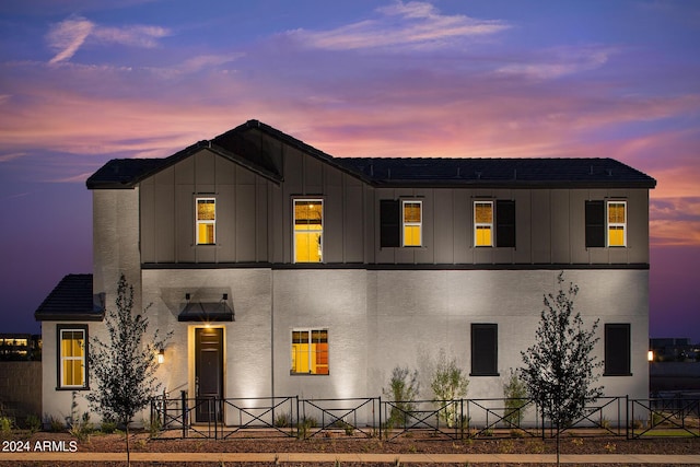 view of front of property with stucco siding, board and batten siding, and fence