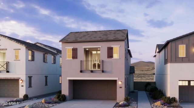 view of front of house with a garage, driveway, a balcony, and stucco siding