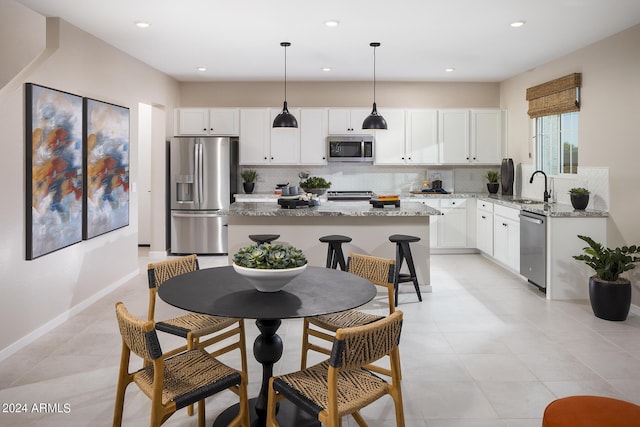 kitchen featuring light stone countertops, backsplash, stainless steel appliances, and a sink