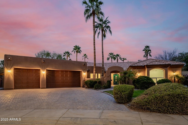 view of front facade with a garage, decorative driveway, and stucco siding