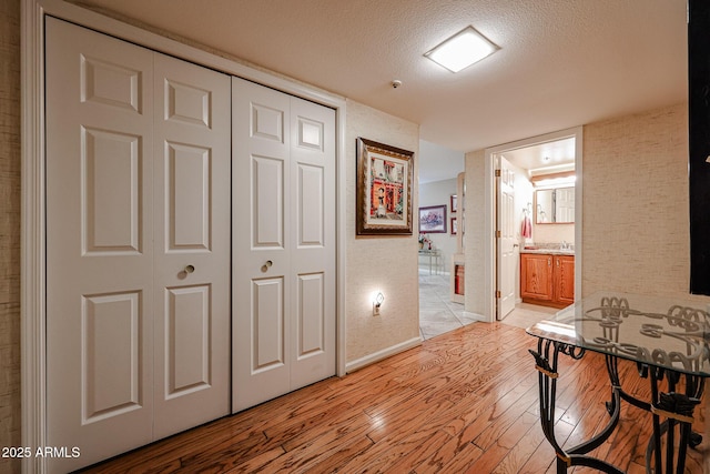 hall with a textured ceiling and light wood-type flooring