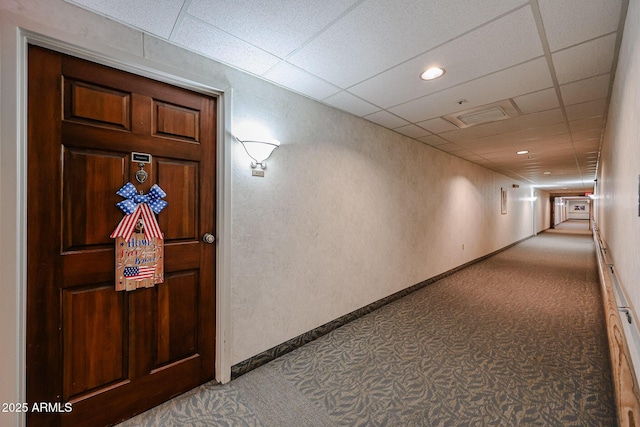 hallway featuring carpet flooring and a paneled ceiling