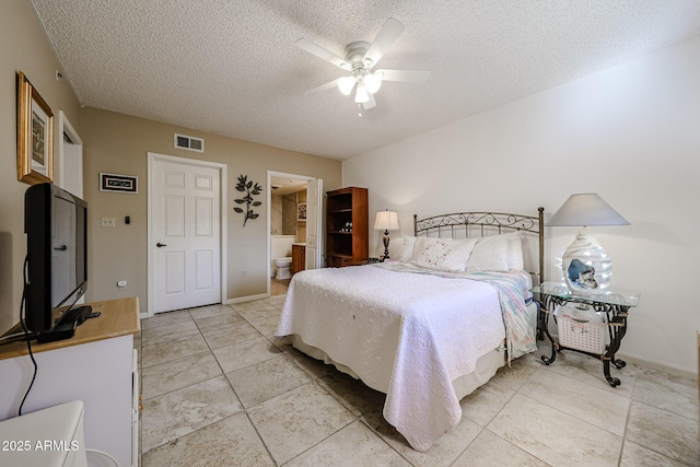 bedroom featuring ceiling fan, ensuite bath, and a textured ceiling