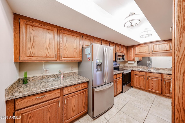 kitchen featuring sink, light tile patterned flooring, light stone countertops, and appliances with stainless steel finishes