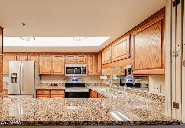 kitchen with appliances with stainless steel finishes, sink, and light stone counters