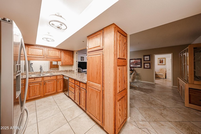 kitchen with light stone counters, light tile patterned floors, stainless steel appliances, and sink