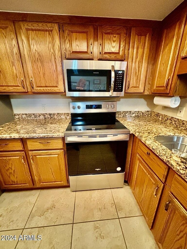 kitchen featuring appliances with stainless steel finishes, light stone countertops, and sink