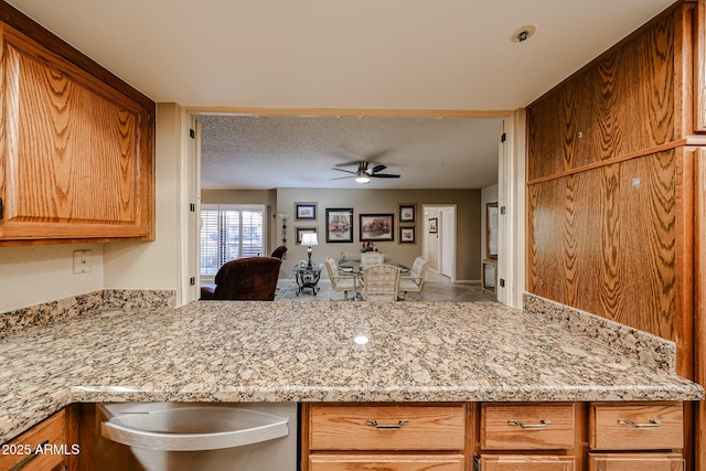 kitchen featuring light tile patterned flooring, ceiling fan, light stone countertops, and a textured ceiling