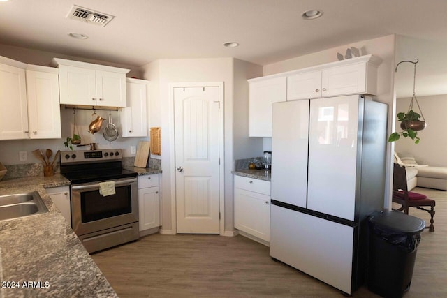 kitchen featuring dark wood-type flooring, white refrigerator, sink, stainless steel range with electric cooktop, and white cabinetry