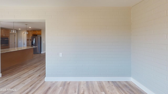 4151 E Clovis Ave, Mesa, AZ 85206 - unfurnished room with light wood-style flooring, baseboards, and brick wall