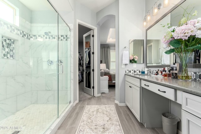 full bath with vanity, a shower stall, a wealth of natural light, and wood tiled floor