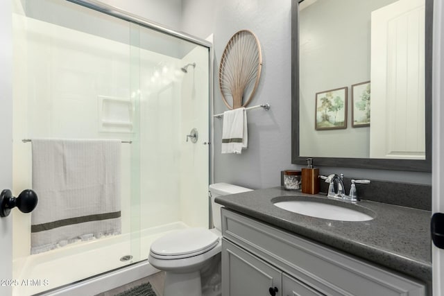 bathroom featuring vanity, toilet, and a shower stall