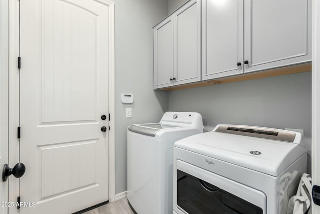 laundry area with washer and dryer, cabinet space, and light wood finished floors