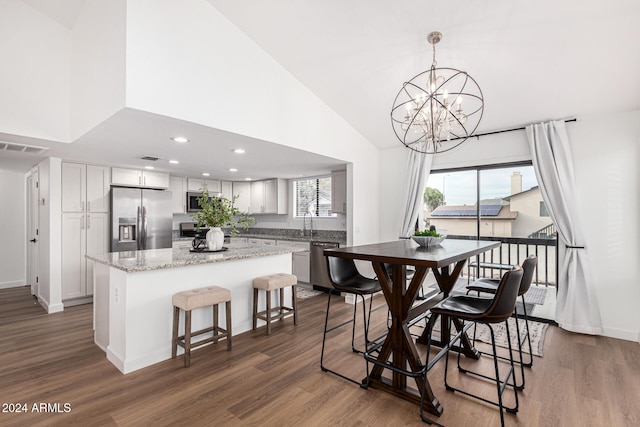 dining room with dark wood-type flooring, a chandelier, and high vaulted ceiling