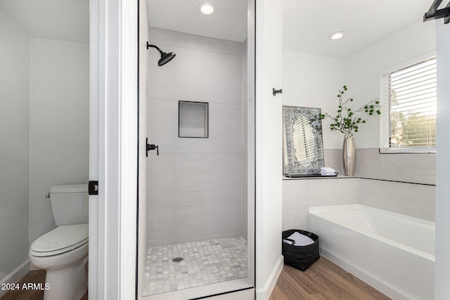 bathroom with hardwood / wood-style flooring, toilet, and shower with separate bathtub