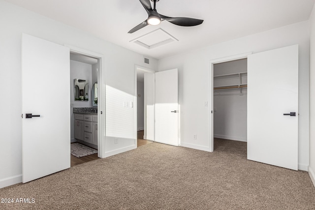 unfurnished bedroom featuring a closet, a walk in closet, carpet floors, ceiling fan, and ensuite bathroom