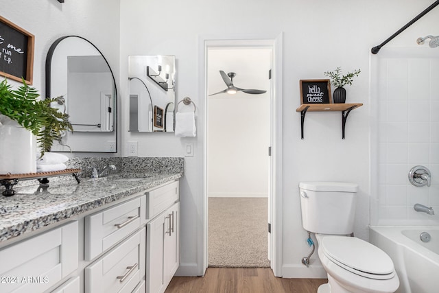 full bathroom with hardwood / wood-style flooring, bathing tub / shower combination, ceiling fan, vanity, and toilet