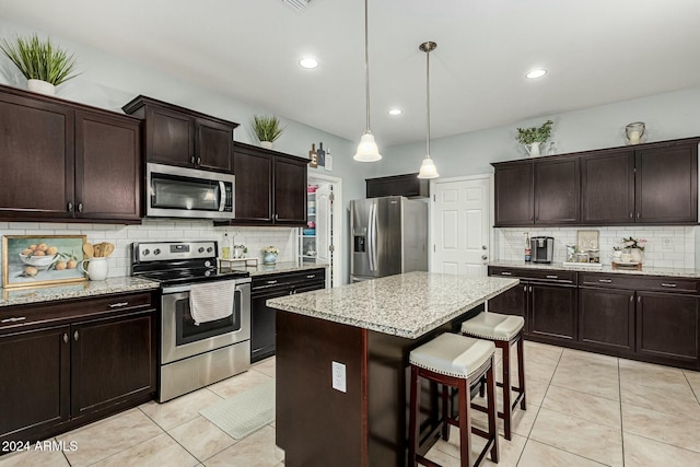 kitchen with stainless steel appliances, a center island, decorative light fixtures, and light tile patterned flooring