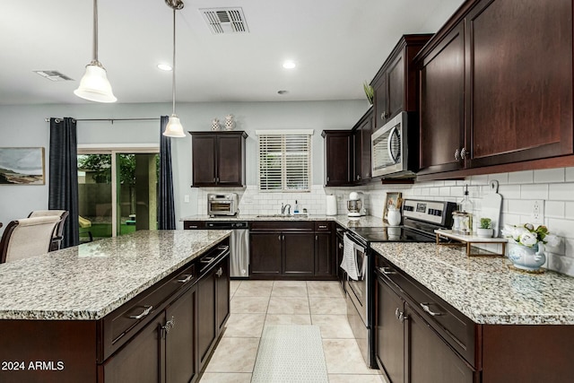 kitchen with stainless steel appliances, visible vents, hanging light fixtures, and a kitchen island