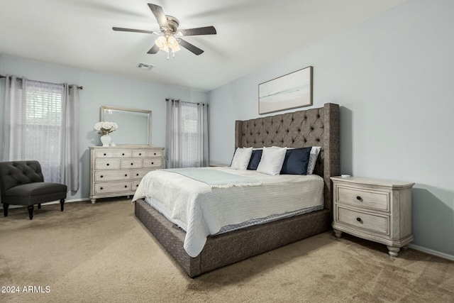 bedroom with ceiling fan, visible vents, baseboards, and light colored carpet