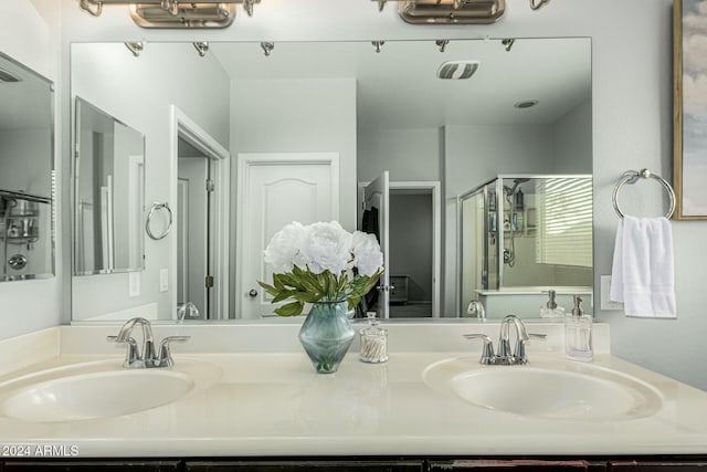 bathroom featuring double vanity, a stall shower, and a sink