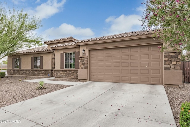 view of front of property with driveway, stone siding, a garage, and stucco siding