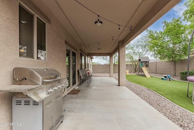 view of patio with area for grilling, a playground, and a fenced backyard