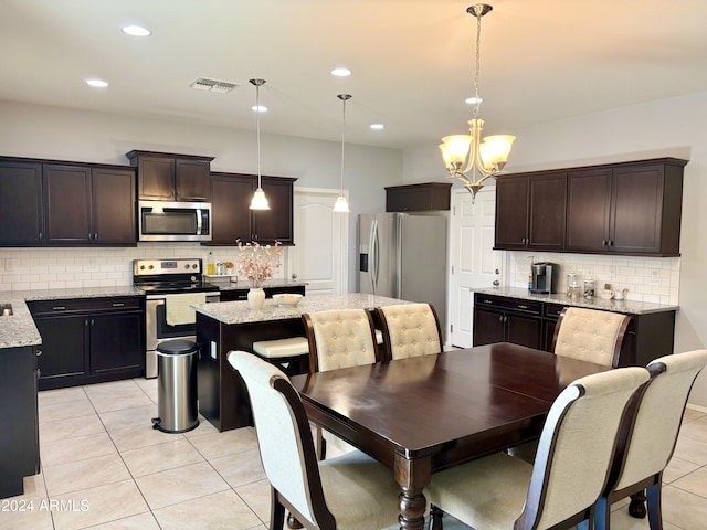 kitchen featuring stainless steel appliances, hanging light fixtures, visible vents, and a center island