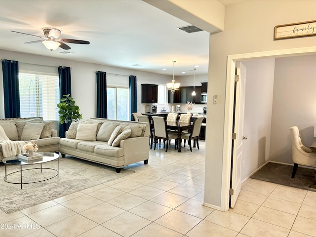 living room featuring ceiling fan with notable chandelier, light tile patterned flooring, and visible vents