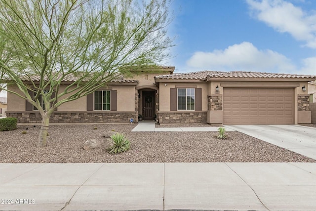 view of front of home with stucco siding, concrete driveway, a garage, stone siding, and a tiled roof