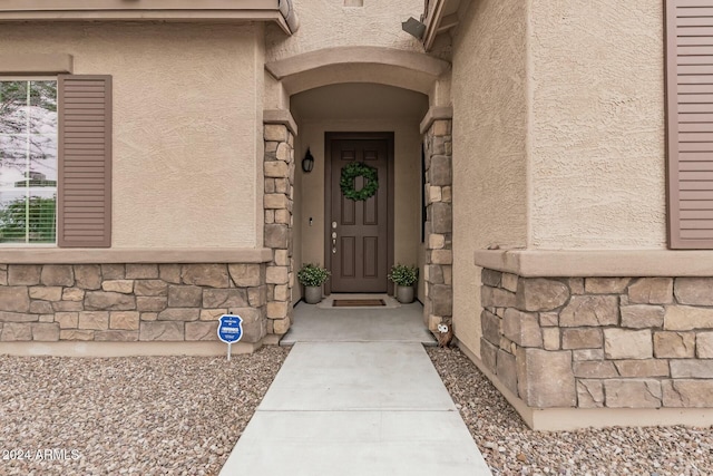 entrance to property featuring stone siding and stucco siding