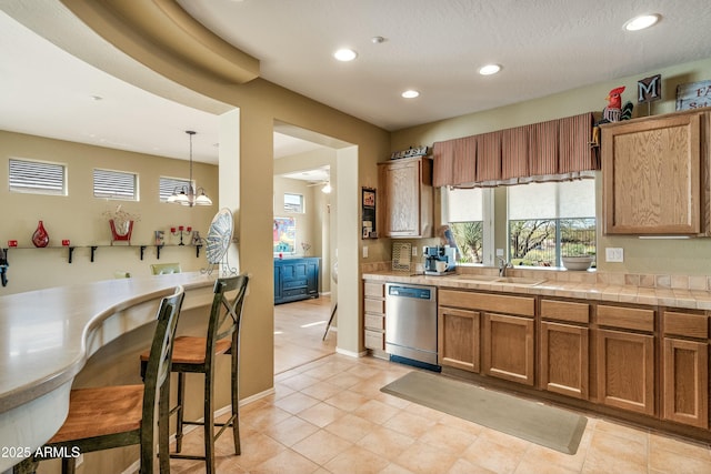 kitchen featuring decorative light fixtures, sink, stainless steel dishwasher, tile counters, and ceiling fan