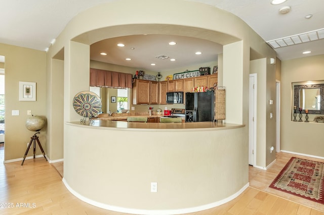 kitchen with light hardwood / wood-style flooring, black appliances, and kitchen peninsula