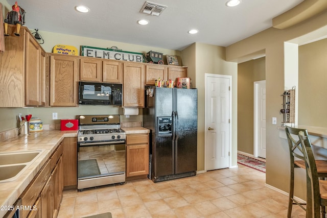 kitchen featuring tile countertops, sink, and black appliances