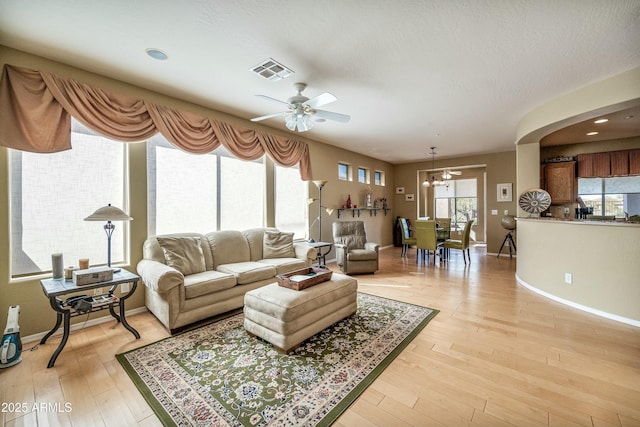 living room featuring ceiling fan, a textured ceiling, and light hardwood / wood-style floors