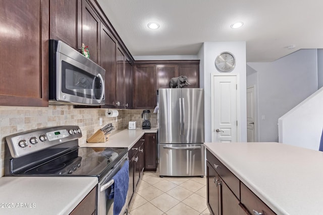 kitchen with dark brown cabinetry, light tile patterned floors, backsplash, and appliances with stainless steel finishes