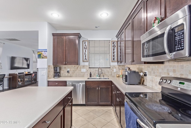 kitchen featuring light tile patterned flooring, dark brown cabinetry, sink, stainless steel appliances, and backsplash