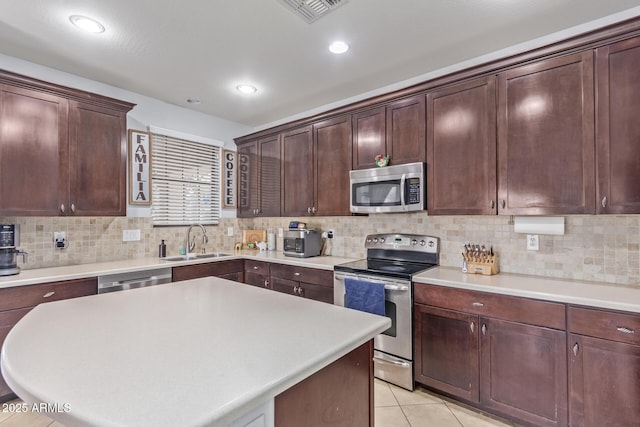 kitchen with light tile patterned flooring, a kitchen island, tasteful backsplash, sink, and stainless steel appliances