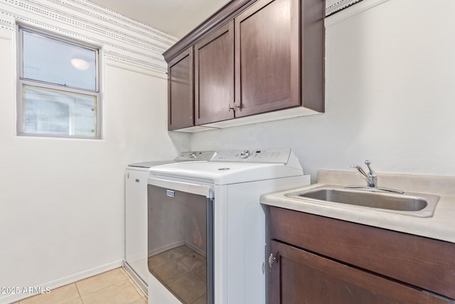 laundry area with cabinets, light tile patterned flooring, separate washer and dryer, and sink