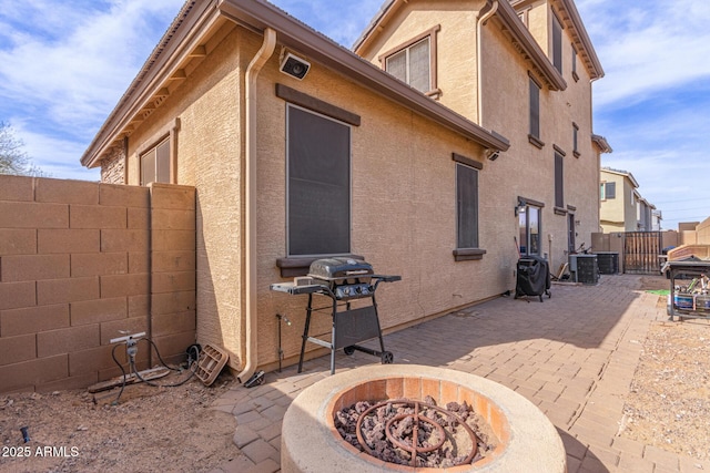 view of property exterior with central AC unit, a patio area, and a fire pit