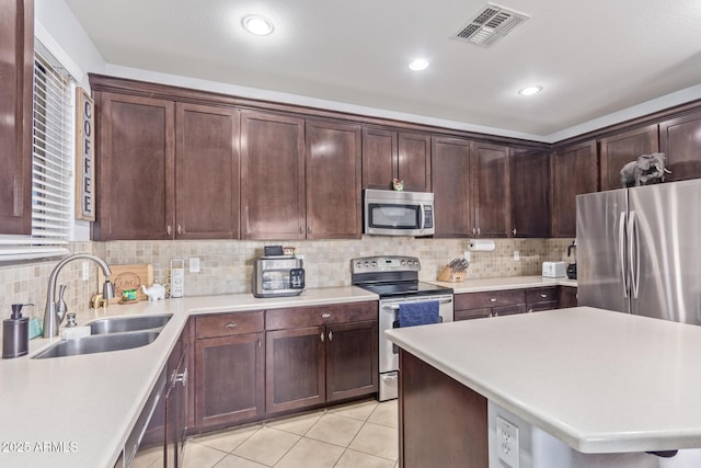 kitchen featuring tasteful backsplash, sink, light tile patterned floors, and stainless steel appliances