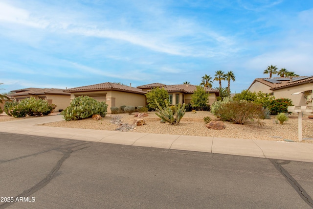 view of front of home with driveway, a tiled roof, an attached garage, and stucco siding