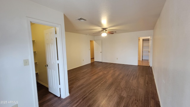 spare room featuring dark wood-type flooring, a ceiling fan, and baseboards