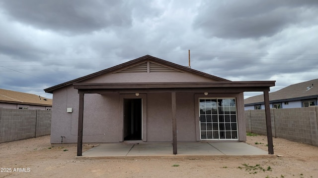 rear view of property featuring stucco siding, a fenced backyard, and a patio area