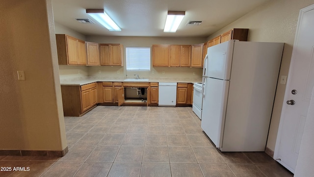 kitchen featuring white appliances, a sink, light countertops, and light tile patterned floors