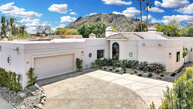 mediterranean / spanish house featuring driveway, a chimney, an attached garage, a mountain view, and stucco siding