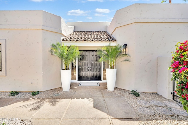 property entrance with a tile roof and stucco siding