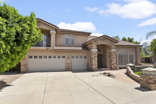 mediterranean / spanish house featuring concrete driveway, an attached garage, stone siding, and stucco siding